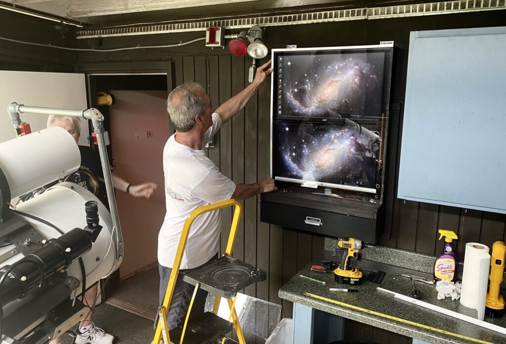 A member working on the camera system at the DuPage Valley Observatory, a galaxy image on the monitors