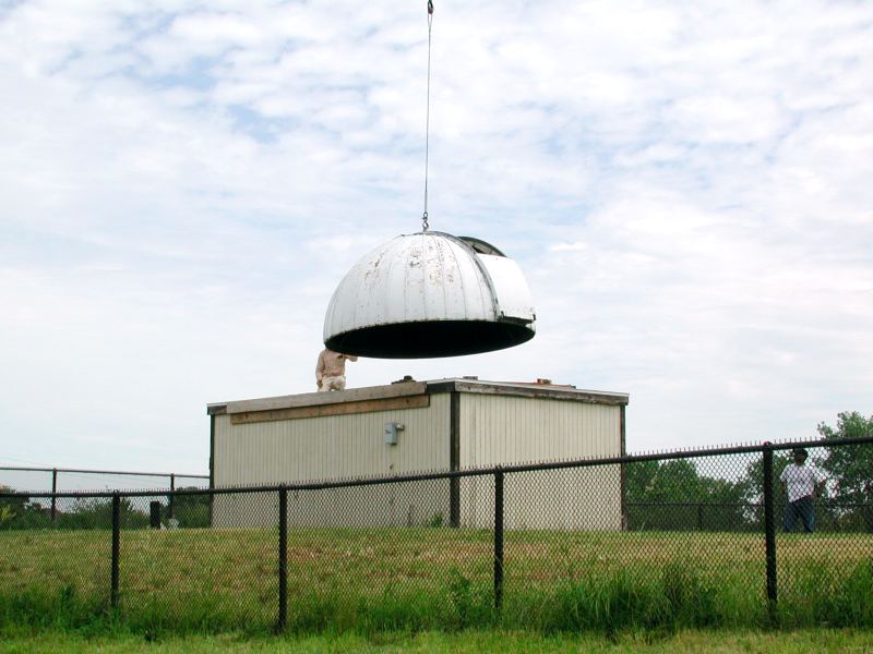 A crane lifting the Riley Observatory’s white dome off the old building