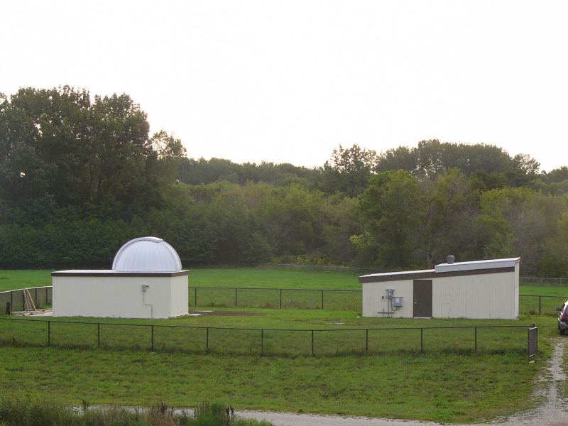 The domed Riley Observatory and the DuPage Valley Observatory side by side in a fenced field