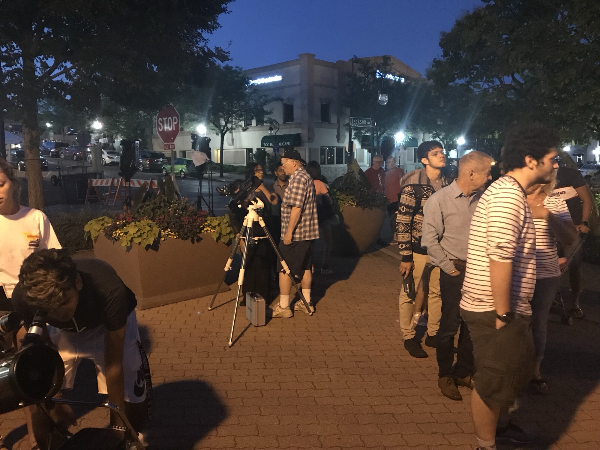 Visitors lined up at club telescopes on the Naperville Riverwalk at dusk