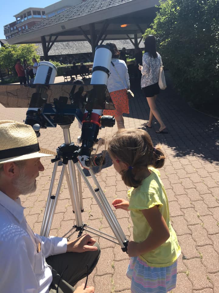 A member showing a young visitor a solar telescope on the Naperville Riverwalk