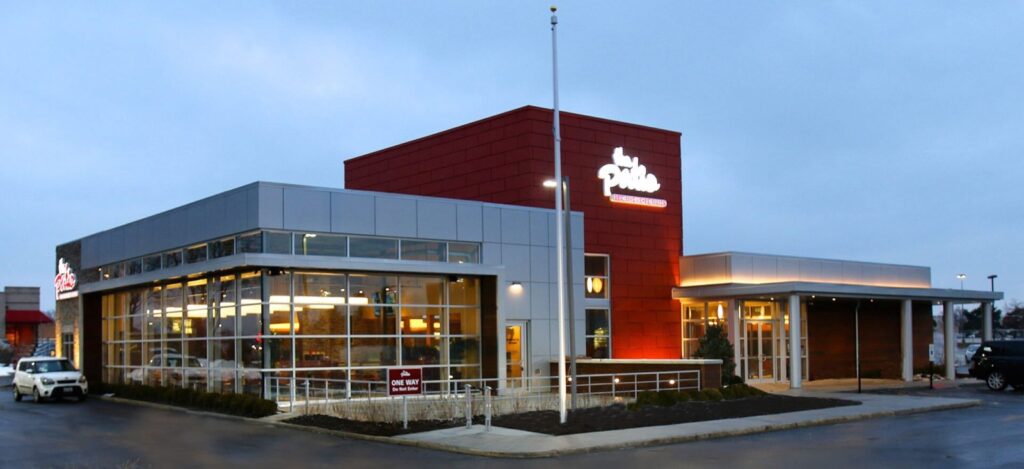 The Patio restaurant in Aurora at dusk: a glass-fronted dining room and a red tower with the restaurant's sign.